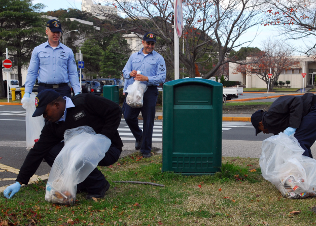 Drei Polizisten in Uniform sammeln Müll an einer Straßenrand auf