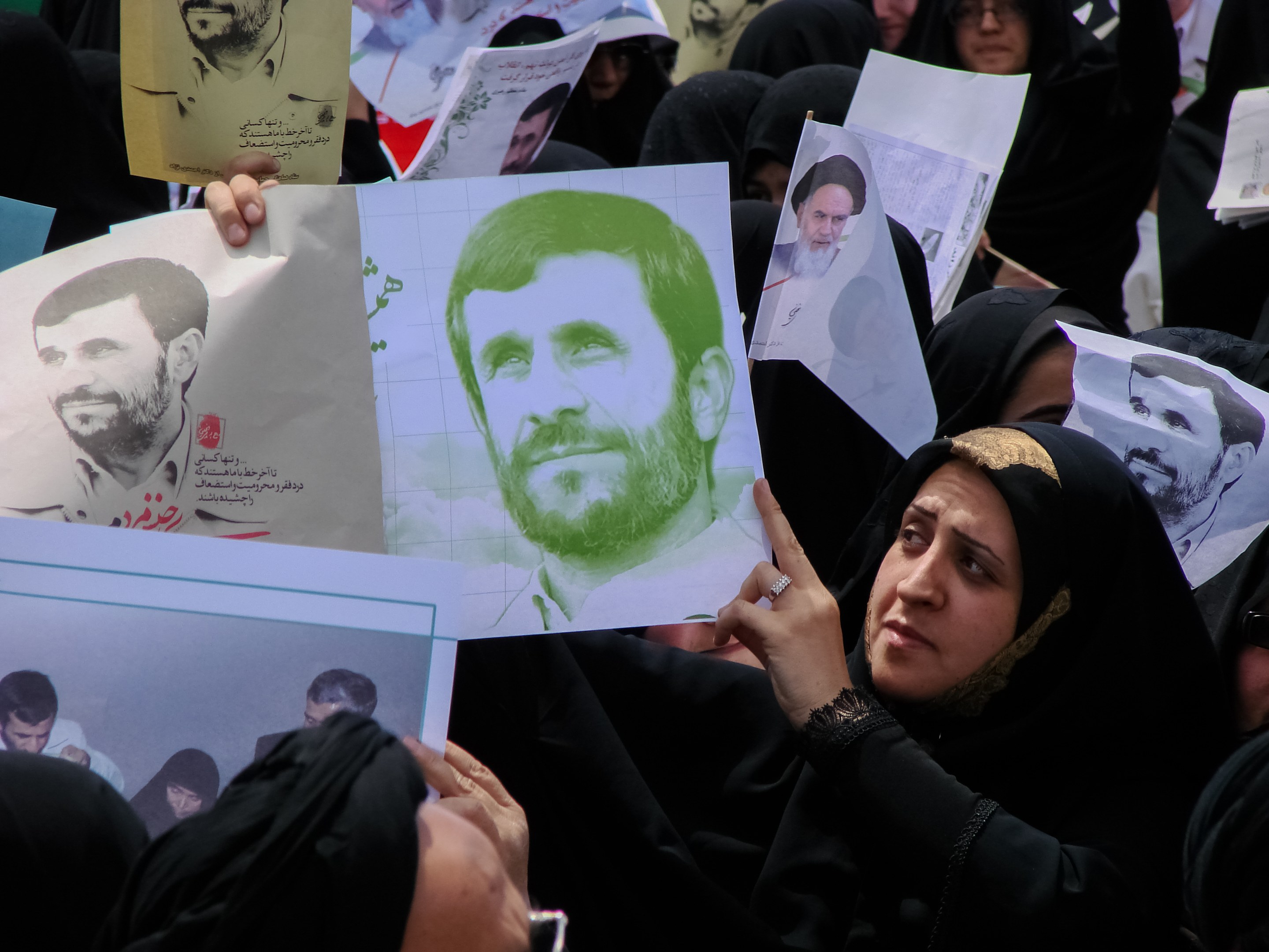 Eine Gruppe iranischer Frauen in schwarzer Kleidung, einige mit Brille, halten Fotos von Präsident Mahmoud Ahmadinejad während einer Kundgebung in Tehran hoch.