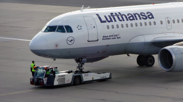 Lufthansa Airbus A319-100 auf dem Frankfurter Flughafen mit einem Bodenfahrzeug und einer Person in der Nähe, bereit zum Start.