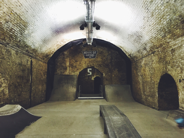 Skatepark mit Ziegelstein-Tunnel, Rampen, Bank und Texttafel sowie Deckenbeleuchtung