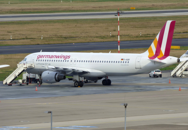 Germanwings Airbus A320-200 am Frankfurt Airport geparkt mit Bodenfahrzeugen, Verkehrskegeln, Pfosten und Gras im Hintergrund.
