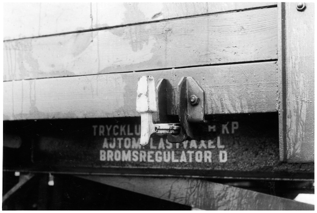 Ein Schwarz-Wei-Foto eines Zugwagens mit einem Metallschloss daran, mit Text.