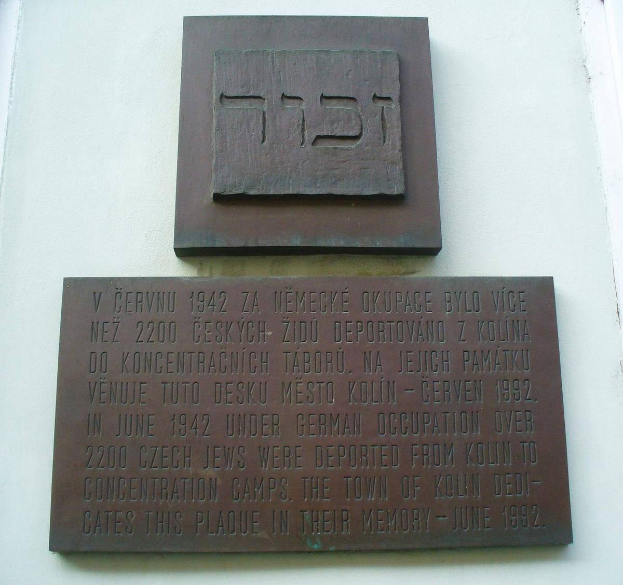 Metallplatte an einer Gebäudewand mit hebräischer Schrift angebracht, wahrscheinlich ein Denkmal zur Ehrung jüdischer Gemeindeglieder.
