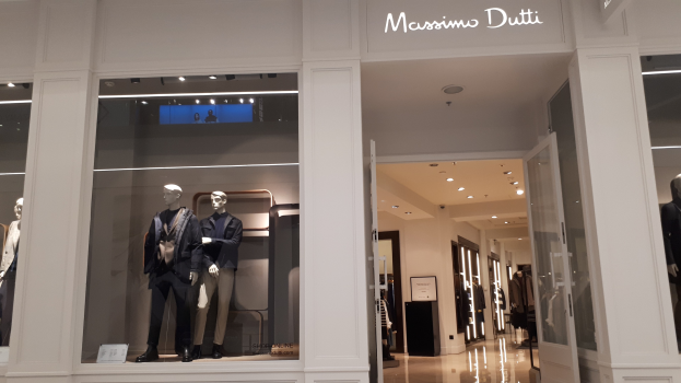 Innenansicht des Massimo Dutti Geschäfts in Mailand mit Schaufensterpuppen in aktueller Mode, Deckenbeleuchtung, Informationsschildern und sichtbarem Boden.