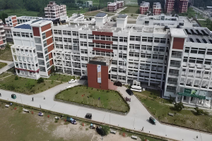 Luftaufnahme eines großen Gebäudes mit Solarpaneelen auf dem Dach, identifiziert als Krankenhaus durch eine Fahne, umgeben von Bäumen, Gras, Fahrzeugen, Menschen, Polen und Teil eines Solarprojekts.