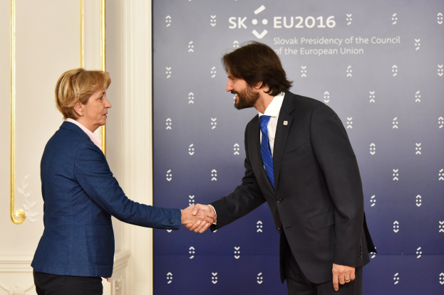Bundeskanzlerin Angela Merkel und Bundespräsident Joachim Gauck schütteln sich lachend vor einem "EU-Gipfel"-Schild und einer Tür die Hände.