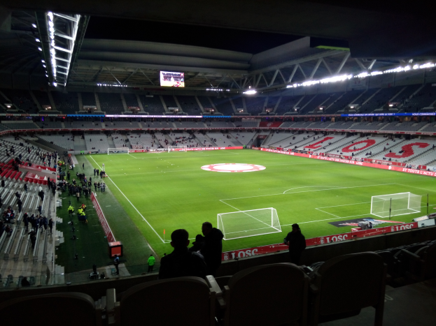 Ein großes Stadion, Estadio Santiago Bernabeu in Madrid, Spanien, voller Zuschauer bei einem Fußballspiel, beleuchtet von Scheinwerfern und einem Bildschirm oben.