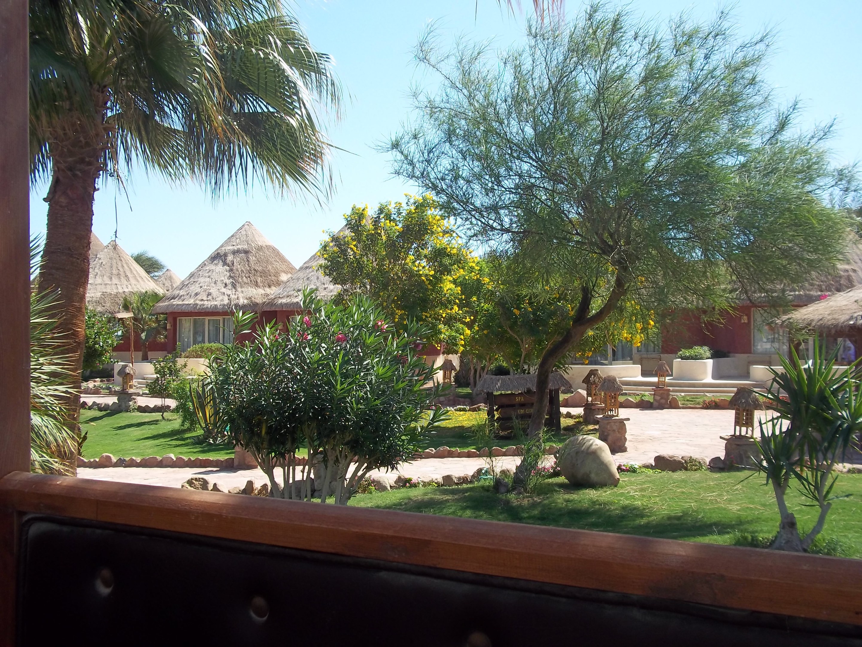 Resortblick mit Hütten, Grünzeug, Felsen, Bank und Himmel.