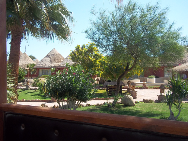 Resortblick mit Hütten, Grünzeug, Felsen, Bank und Himmel.