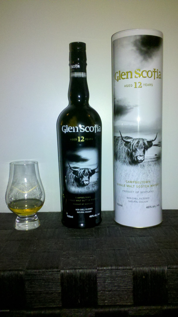 Flasche Glen Scotia 12 Jahre alter Scotch-Whisky und ein Glas desselben Whiskys auf einem hellen Holztisch.