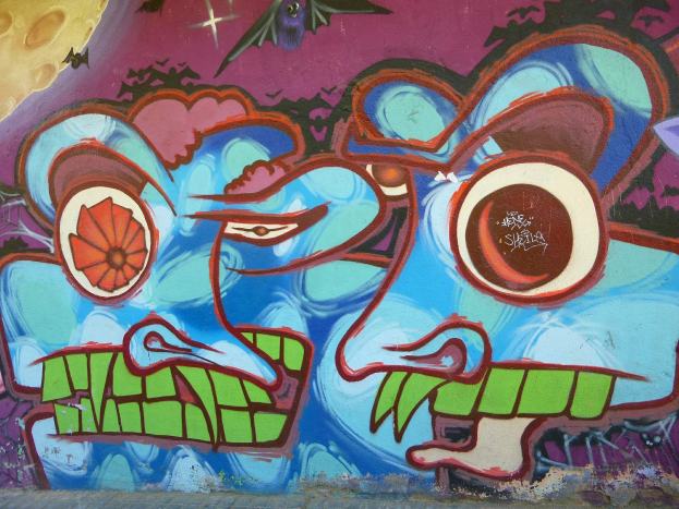 Ein lebendiges Wandgemälde mit farbenfrohen Formen und Graffiti auf der Seite eines Gebäudes.