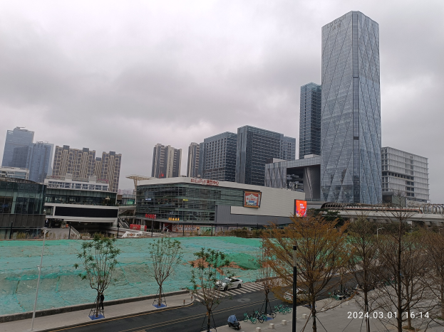 Eine Baustelle in Seoul, Südkorea mit hohen Gebäuden, Fahrzeugen, Bäumen, Masten, Schildern, einer Hütte und einem bewölktem Himmel im Hintergrund.