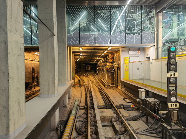 Eine U-Bahn-Station der London Underground mit einem Zug auf den Schienen, beleuchtet von Deckenlampen, mit einer Plattform und Säulen auf der linken Seite und einem Signal mit einem Pfahl auf der rechten Seite.