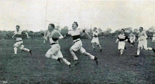 Schwarzes und weißes Foto von Männern, die Rugby auf einem grasigen Feld mit Bäumen und Pfählen im Hintergrund spielen, beschriftet mit "1930er Jahre Rugby League."