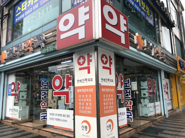 Außenansicht einer modernen Glasfassade-Apotheke in Seoul, Südkorea, mit einer Beschriftung, die sie als erste Apotheke der Stadt identifiziert.