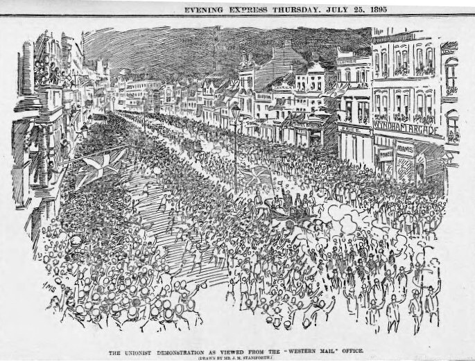 Schwarze und weiße Zeichnung einer Menge, die zwischen Gebäuden eine Straße entlanggeht, mit Text oben und unten: "Die Unionistendemonstration, wie sie vom Western Mail Office aus zu sehen ist."