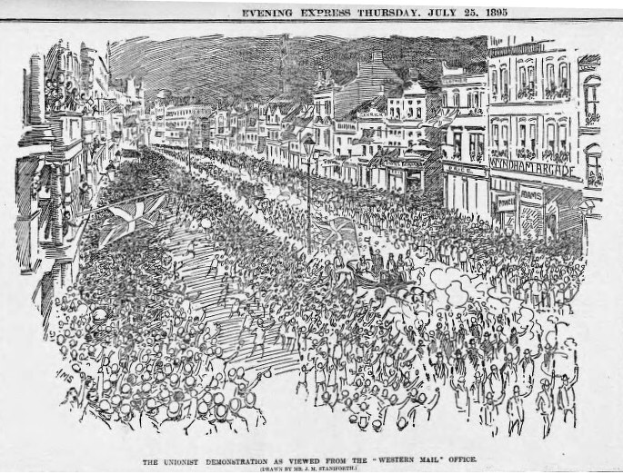Schwarze und weiße Zeichnung einer Menge, die zwischen Gebäuden eine Straße entlanggeht, mit Text oben und unten: "Die Unionistendemonstration, wie sie vom Western Mail Office aus zu sehen ist."